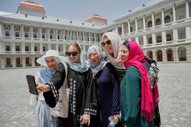 Maryam, uma jovem afegão em seu primeiro dia de treinamento, para se tornar um guia turístico, ajuda a adaptar a turista australiana de 82 anos Suzanne Sandral, seu hijab em Cabul, Afeganistão, na quarta-feira, 28 de maio de 2025 (AP Photo/Ebrahim Noroozi)