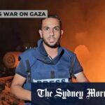 Os palestinos caminham pelo rosto do acampamento na praia em Gaza City no domingo.