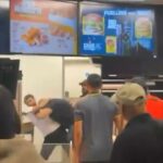 Este é o momento chocante (foto), um cliente do McDonald's pulou sobre o balcão e começou a discutir com a equipe
