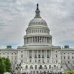 O Senado toma medidas para combater o jogo problemático no Exército dos EUA. O edifício do Capitólio dos Estados Unidos em Washington, DC, visto de frente com uma bandeira americana que voa, sob um céu nublado.