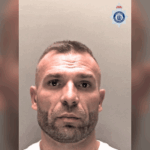 Polícia de um homem com cabelos curtos e barba aparada, com um top branco, levado contra um fundo normal. O crachá da polícia de Cheshire é visível no canto direito. O homem prendeu oito meses após o ataque do cassino