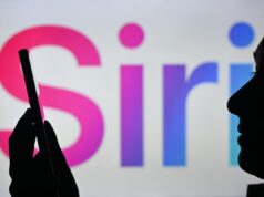 A reformulação do Siri da Apple pode incluir a exclusão automática de bate-papos An image of a woman holding a cell phone in front of the Siri logo displayed on a computer screen.