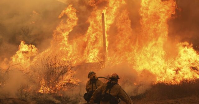 Uma habitação no carrinho de golfe de passeios na propriedade, enquanto o Canyon Fire queima em Hasley Canyon, Califórnia.