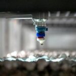 Uma garagem industrial com cinco homens que trabalham em uma máquina.