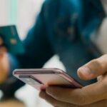 Pessoa que tem um telefone celular com cartão bancário