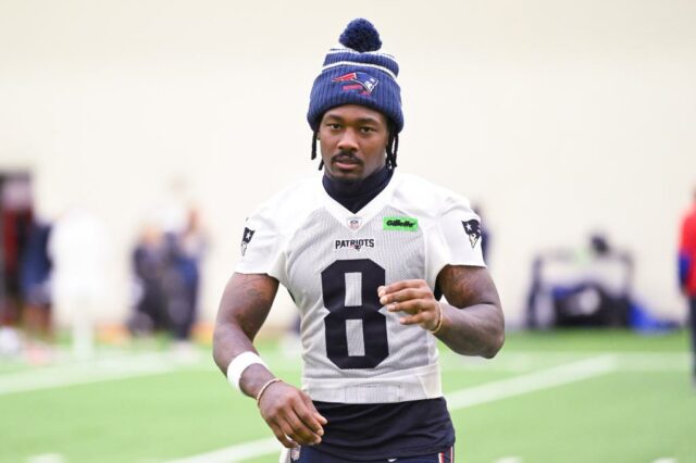 O jogador do New England Patriots em um uniforme segurando futebol.
