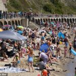 Pessoas que gostam do clima quente em Sunny Sands Beach, em Folkestone, Kent, 12 de julho