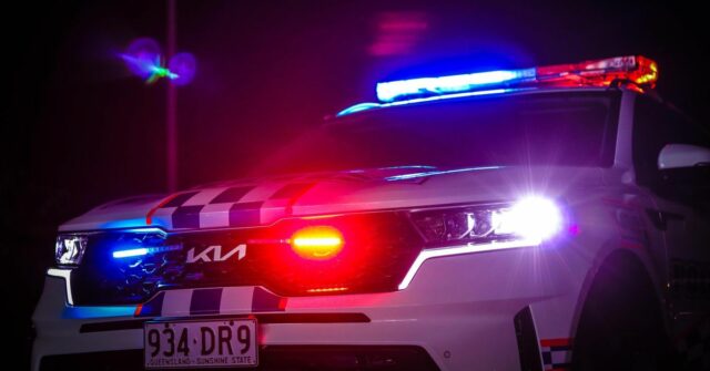 Um carro da polícia da QLD Kia à noite com suas sirenes em