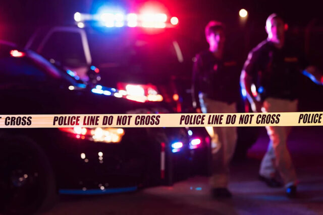 Megan Varner/Getty Police Officer com fita de polícia (imagem de estoque)