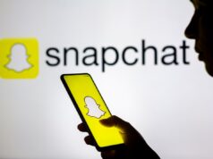 A lente nova do Snapchat permite que você produz fotos de IA utilizando a mensagem motiva In this photo illustration, a woman's silhouette holds a smartphone with the Snapchat logo displayed on the screen and in the background.