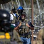 A US Immigration and Customs Enforcement agent watches as Customs and Border Protection officers hold the line against protestors who responded to a Federal Immigration raid at Glass House Farms in Camarillo, California, July 10, 2025.