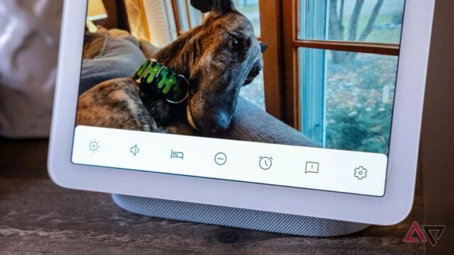O alto -falante do Nest Audio com suas luzes ativas, sentado em uma pequena pilha de livros