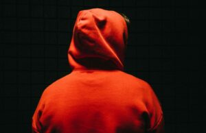 Apple em exame legal na UE sobre aplicações de roubo Apple sob escrutínio legal na UE Over Scam Apps | Rosto escondido por capuz e escuridão