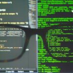 A Apple parece pronta para fazer duas alterações de segurança do iOS 26 para tornar os iPhones mais seguros | Código em monitores vistos através de óculos