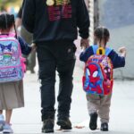 Homem andando dois filhos para a escola.