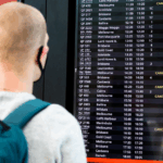 Um viajante olha para um quadro de aeroporto mostrando vários voos cancelados.