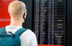 Aussies pode obter composição em dinheiro para atrasos de voo, cancelamentos Um viajante olha para um quadro de aeroporto mostrando vários voos cancelados.