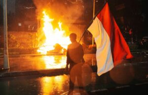 Austrália emite aviso de viagem para destino turístico popular em meio à agitação Um homem carrega a bandeira nacional indonésia quando um cargo de polícia de trânsito é queimado durante um protesto após a morte de um piloto de entrega em confrontos entre policiais e estudantes que protestam contra os legisladores, fora da sede da polícia regional em Jacarta, Indonésia, sexta -feira, 29 de agosto de 2025. (AP Photo/Tatan Syuflana)