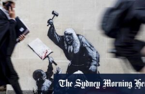 ‘Brutalidade desencadeada’: New Banksy na parede da corte descreve o manifestador de ataques de ataque Um oficial de segurança tenta bloquear a obra de arte à medida que os fotógrafos da polícia chegam.
