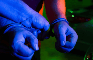 Mulher acusada de morte no norte da Austrália do Sul Duas mãos em algemas policiais.