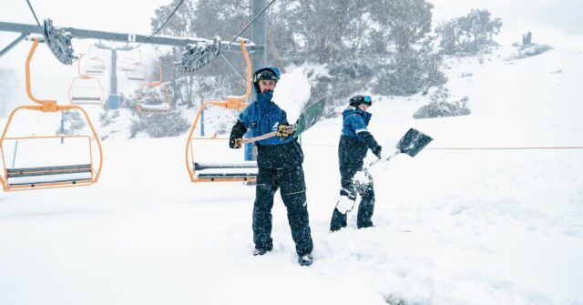 Os esquiadores trabalham para limpar a neve froma cidrelift em Falls Creek, Victoria.