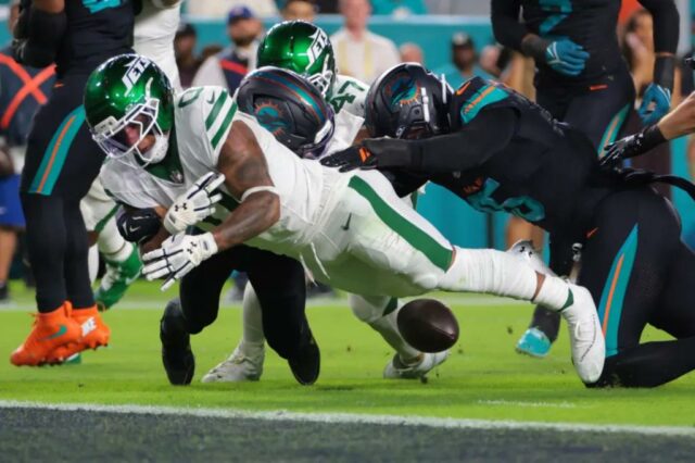 O New York Jets correndo Braelon Allen (0) atrapalha a bola contra o defensivo de Miami Dolphins, Elijah Campbell (22).