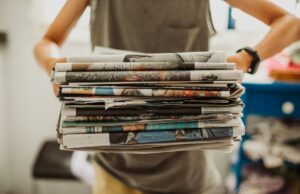 O Google não está brincando em relação ao corte de preços, também diminuindo a associação dos pés A person holding a pile of newspapers.