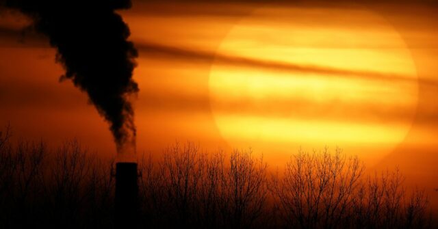 As emissões de uma usina a carvão estão em silhueta contra o sol poente