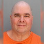 Canecas de um homem careca em uma camisa laranja.