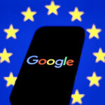 European Union flag displayed on a laptop screen and Google logo displayed on a phone in front of it