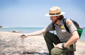 Por que existe areia preta na costa? O que aprender sobre magnetita em Michigan Um guarda florestal do Serviço Nacional de Parques no Sleeping Bear Dunes National Lakeshore mostra areia carregada de magnetita na praia do parque.