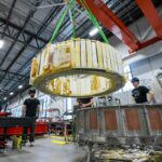 Engineers watch as a magnet is moved inside Commonwealth Fusion System's building.