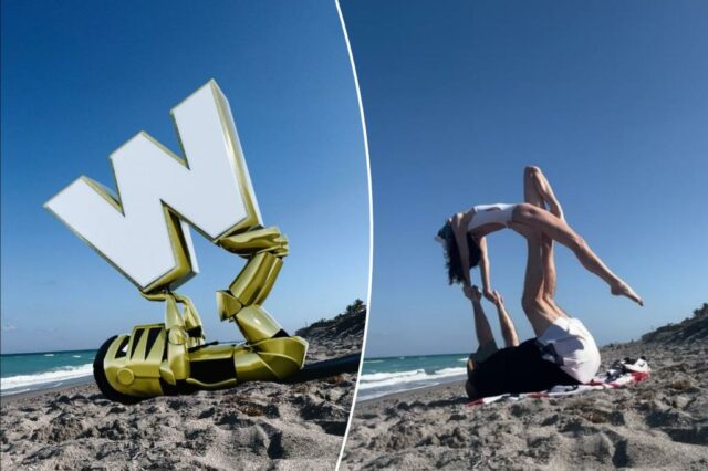 Um homem de costas em uma toalha de praia que apoia uma mulher em uma pose acrobática nos pés.