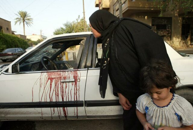 Manchas de sangue em um carro branco; Uma mulher e uma criança estão por perto.