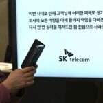 A woman uses her mobile phone while waiting to replace her USIM ship in front of an SK Telecom branch in Seoul on April 28, 2025.