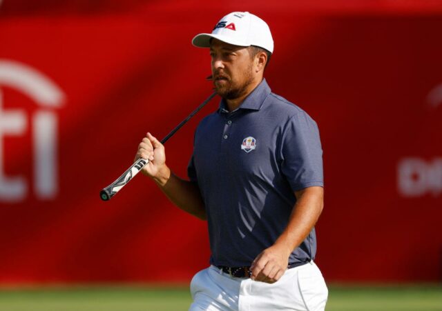 Golfer Xander Schauffele andando com um clube de golfe por cima do ombro.