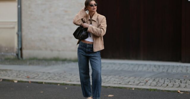 PARIS, FRANÇA - 20 DE MAIO: Ellie Delphine usa brincos dourados, um colar da Missoma, uma blusa / camisa bege oversized sem ombros da The Frankie Shop, calças jeans / jeans azuis de perna larga da H&M, uma bolsa de couro preta da Neous, sandálias T / sapatos de salto alto da Neous, durante uma sessão de fotos de moda de estilo de rua, em 20 de maio de 2024 em Paris, França. (Foto de Edward Berthelot/Getty Images)