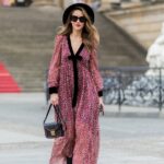 Alba Garavito Torre usa óculos de sol pretos da Ray Ban, brincos grandes de pérolas brancas, camisa branca com gola grande recortada em renda, capa oversized de feltro / lã bege, calça palazzo de lã / feltro bege combinando, bolsa preta de couro brilhante com babados, pulseira Love dourada da Cartier, pulseira dourada, anéis dourados, sapatos de couro marrom com salto agulha, durante sessão de fotos de moda street style, em outubro 28 de outubro de 2021 em Paris, França.