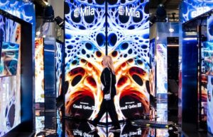 A IA fará ou prejudicará o Canadá? Criadores de tendências e cientistas pedem ainda mais barreiras de proteção Uma mulher com cabelo castanho escuro está dentro de um escritório de tecnologia.