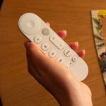 Um Google TV Streamer ao lado de uma TV e um controle remoto
