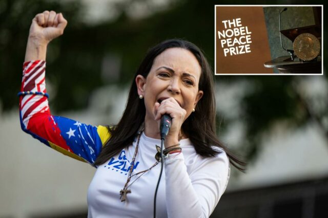 A líder da oposição Maria Corina Machado falando ao microfone com o braço direito levantado em punho.