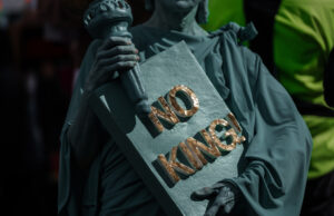 A maioria dos americanos concorda: Trump é um ditador que está destruindo o país Um manifestante carrega uma placa enquanto se manifesta no corredor da rua 14 com U antes de marchar para o National Mall durante um protesto No Kings em Washington, sábado, 18 de outubro de 2025. (AP Photo/Jose Luis Magana)