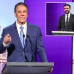 Andrew Cuomo em um pódio de debate com telas mostrando um prédio e