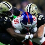 Beaux Collins é abordado no jogo por Kool-Aid McKinstry (4) e Pete Werner (20) depois de fazer uma recepção durante a derrota dos Giants na Semana 5 para o Saints.