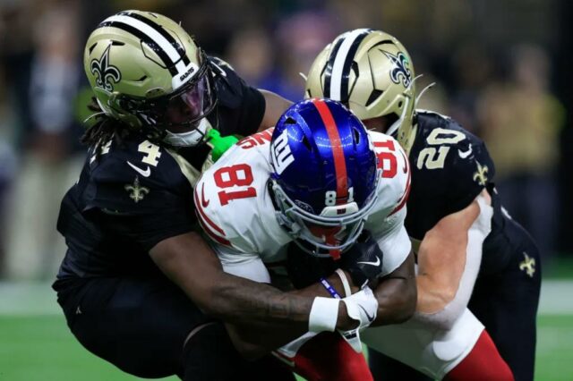Beaux Collins é abordado no jogo por Kool-Aid McKinstry (4) e Pete Werner (20) depois de fazer uma recepção durante a derrota dos Giants na Semana 5 para o Saints.