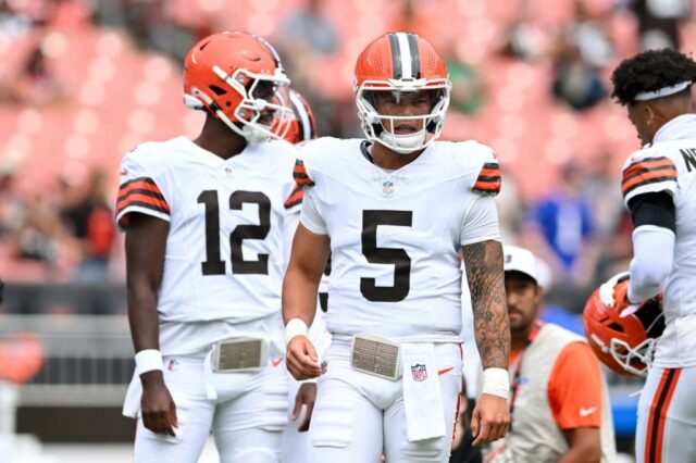 O jogador de Cleveland Browns usando Jersey Número 5 com tatuagens de braço visível fica no campo ao lado de outro jogador.