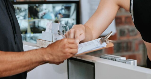 Uma jovem dedicada sentada na academia, profundamente focada em seu telefone, mostrando a mistura de concentração e relaxamento durante as rotinas de treino.