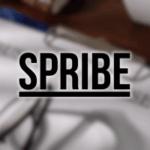 A Comissão de Jogos do Reino Unido suspende a licença do Spribe em meio a não conformidade de hospedagem e disputas de IP. Logotipo SPRIBE em letras pretas em negrito com sublinhado, exibido sobre um fundo desfocado mostrando papéis, óculos e uma mesa