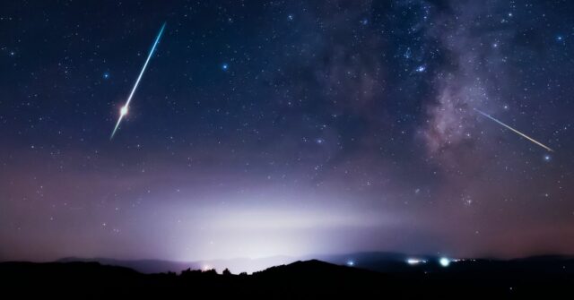 Estrelas da Via Láctea com trilhas de chuva de meteoros e silhuetas rurais.