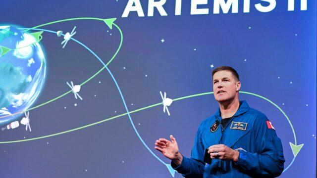 Um homem falando. Atrás dele está uma imagem da terra.